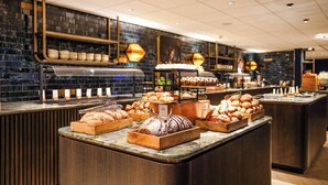 A bakery counter with various baked goods displayed in wooden trays and a bread display. - DoubleTree by Hilton Royal Parc Soestduinen (Soest)