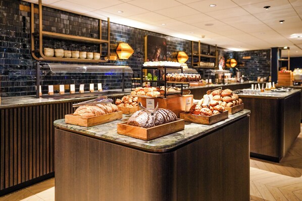 A bakery counter with various baked goods displayed in wooden trays and a bread display.