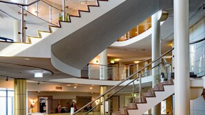 A multi-level interior with a central spiral staircase, glass railings, and a polished marble floor. - DoubleTree by Hilton Royal Parc Soestduinen (Soest)