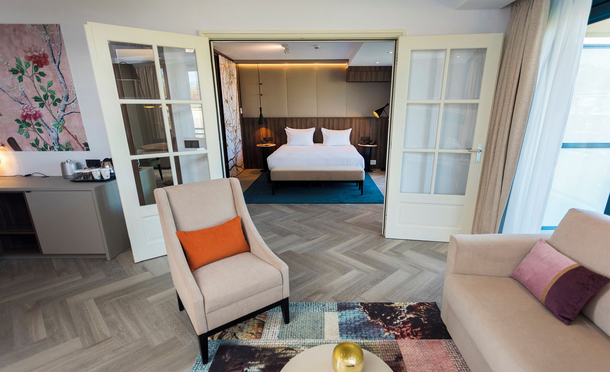 A hotel room with a bed, a desk, a chair, and a sofa.