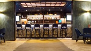 A bar area with a counter, multiple stools, and a variety of bottles. - DoubleTree by Hilton Royal Parc Soestduinen (Soest)