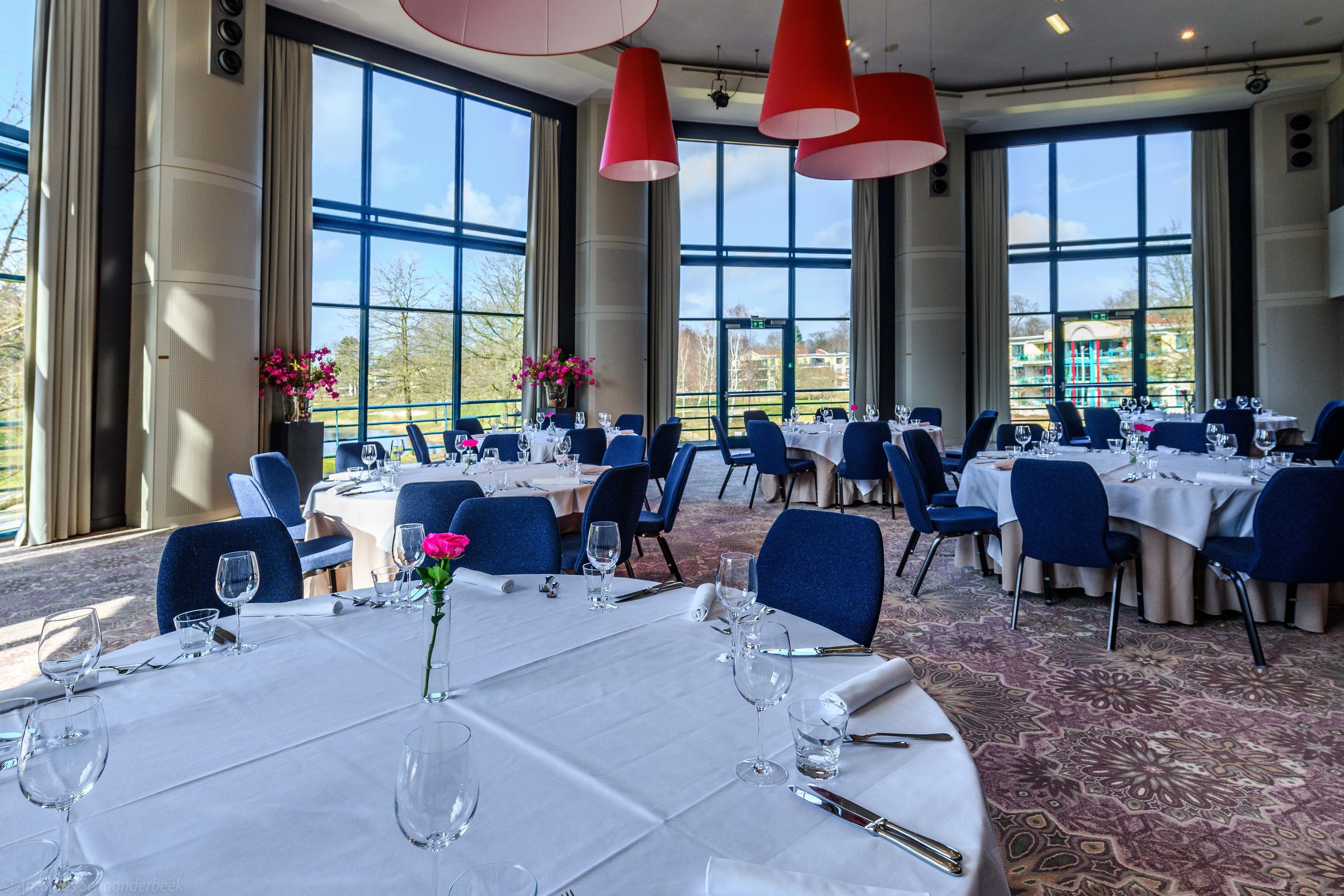 Un comedor con mesas listas para el servicio, ventanas amplias y vistas al exterior.