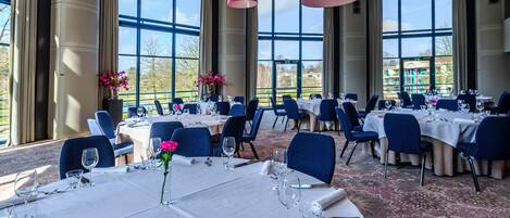 Un comedor con mesas listas para el servicio, ventanas amplias y vistas al exterior.