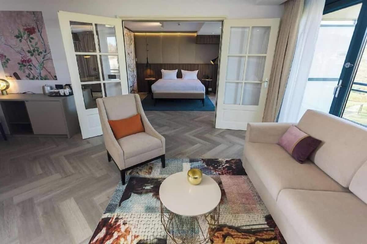 Ein Hotelzimmer mit Bett, Sofa, Couchtisch, Schreibtisch und einem Bild an der Wand.