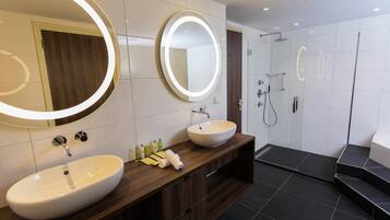 Un baño moderno con dos lavamanos, un espejo grande y una zona de ducha.