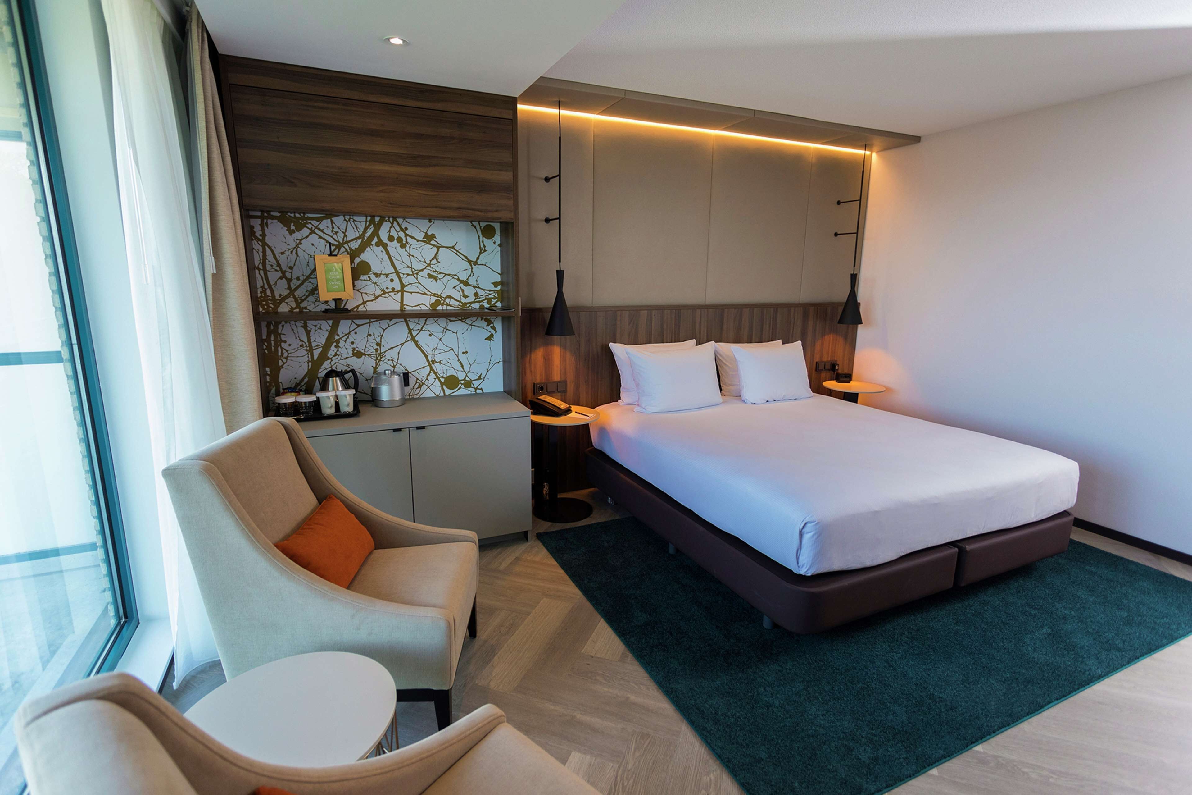 A modern hotel room with a bed, a desk, and a chair.