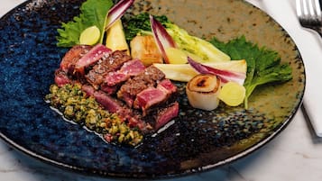 Un plato de comida con una copa de vino tinto sobre una mesa.