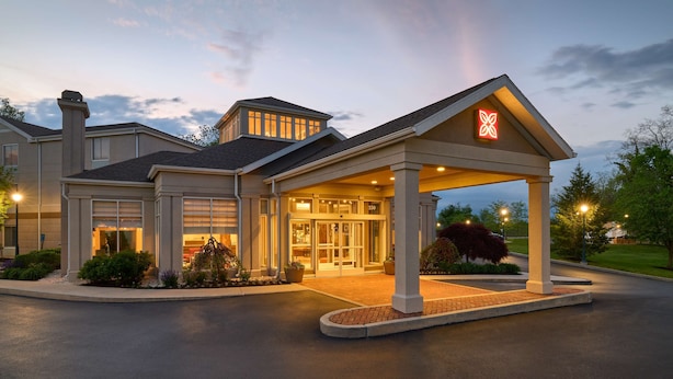 A hotel entrance with a covered lobby, a prominent logo, and a well-maintained exterior.