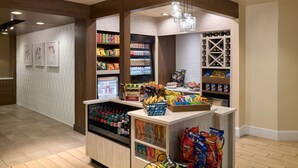 A well-lit snack bar with shelves stocked with various snacks, beverages, and a refrigerated section.