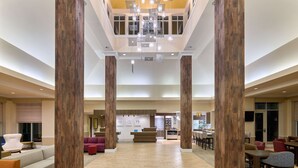 A spacious lobby with high wooden columns, a reception desk, and seating areas.