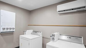 Un cuarto de lavado con dos lavadoras de carga frontal y un equipo de aire acondicionado montado en la pared.