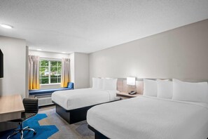 A hotel room with two beds, a desk, a chair, and a window with curtains. - Microtel Inn by Wyndham Georgetown (Georgetown)