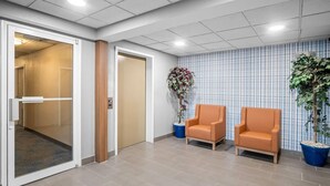 A reception area with two chairs, a potted plant, and a patterned wall. - Microtel Inn by Wyndham Georgetown (Georgetown)