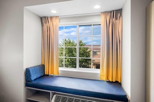 Una habitación con ventana, un banco y cortinas.