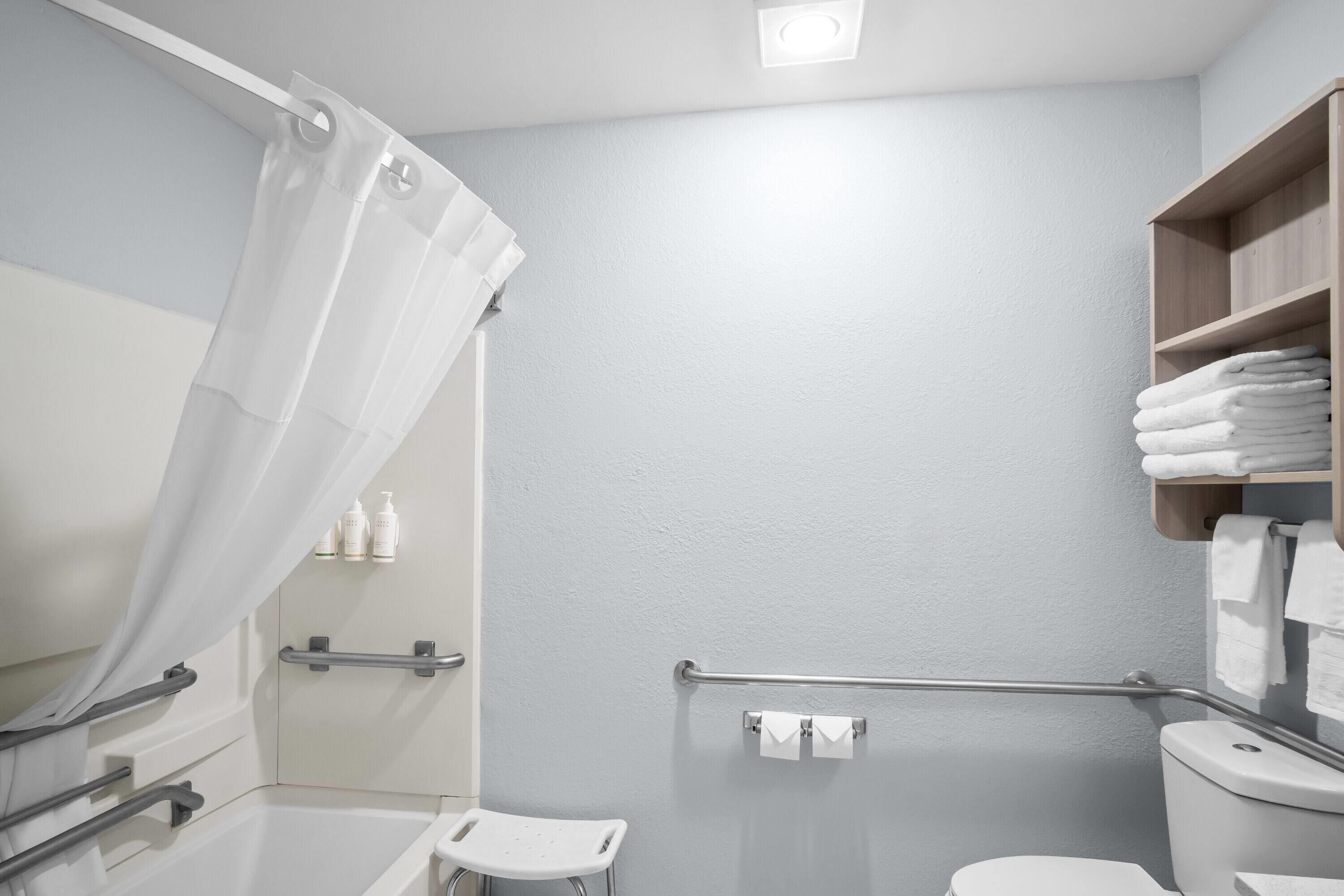 Ein Badezimmer mit Dusche, Toilette und einem Handtuchregal.