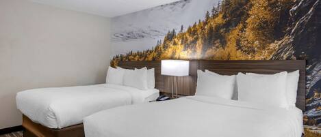 A hotel room with two beds, a large painting of a forest, and a nightstand with a lamp.