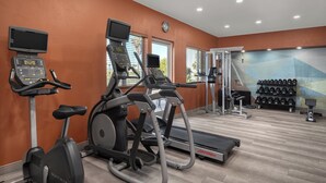 Une salle de sport équipée de tapis de course, d’un appareil elliptique et d’un banc de musculation.