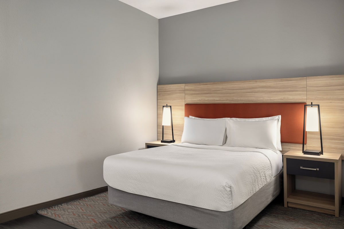 Een hotelkamer met een bed, nachtkastjes en lampen.