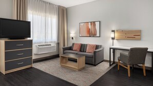 Un salon moderne avec un téléviseur à écran plat, un canapé gris, une table basse en bois et un fauteuil gris.