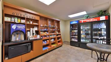 Un área de kitchenette con microondas, cafetera y refrigerador lleno de bebidas.