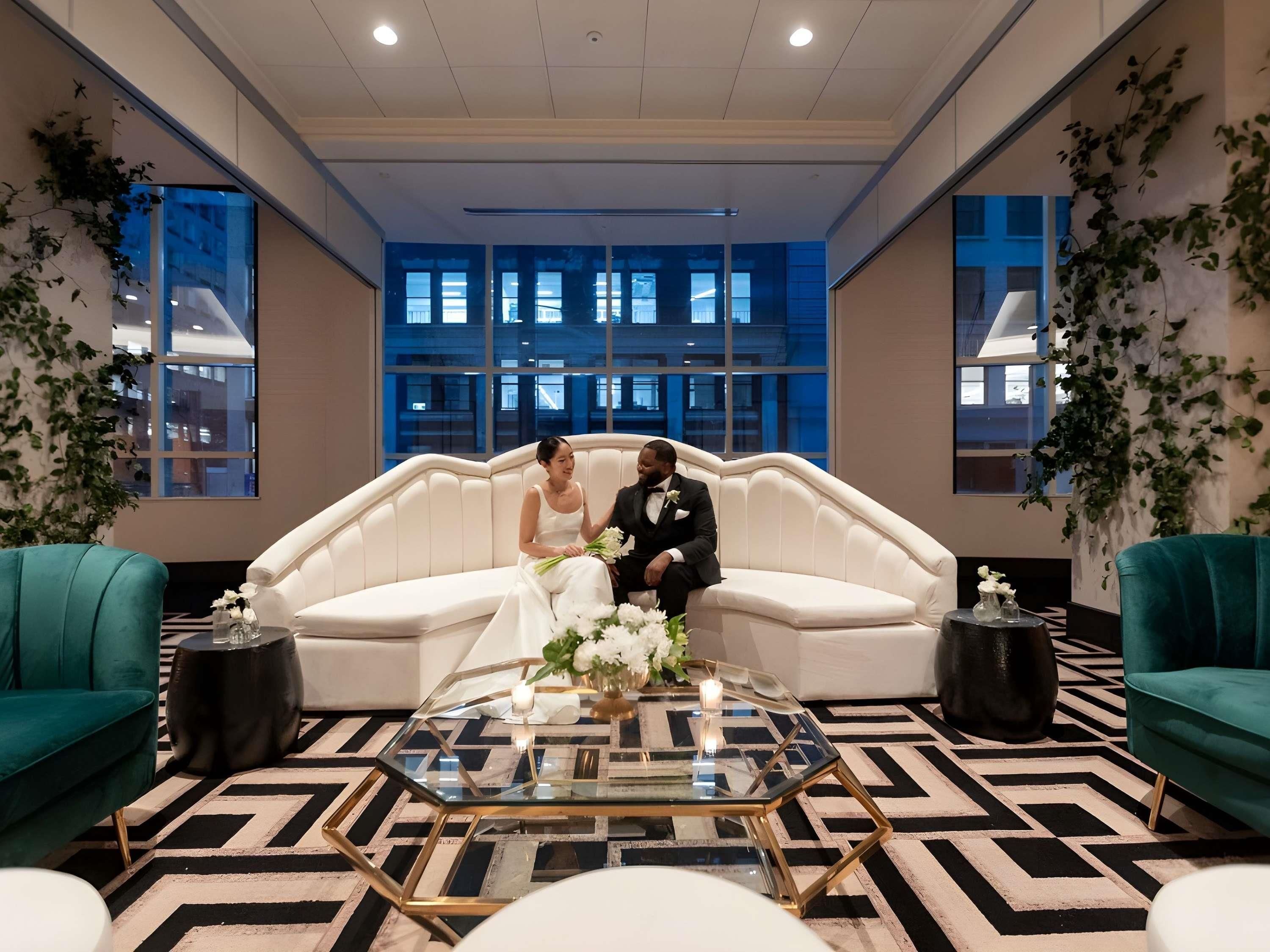 A modern room with a white sofa, teal armchairs, and a glass coffee table.