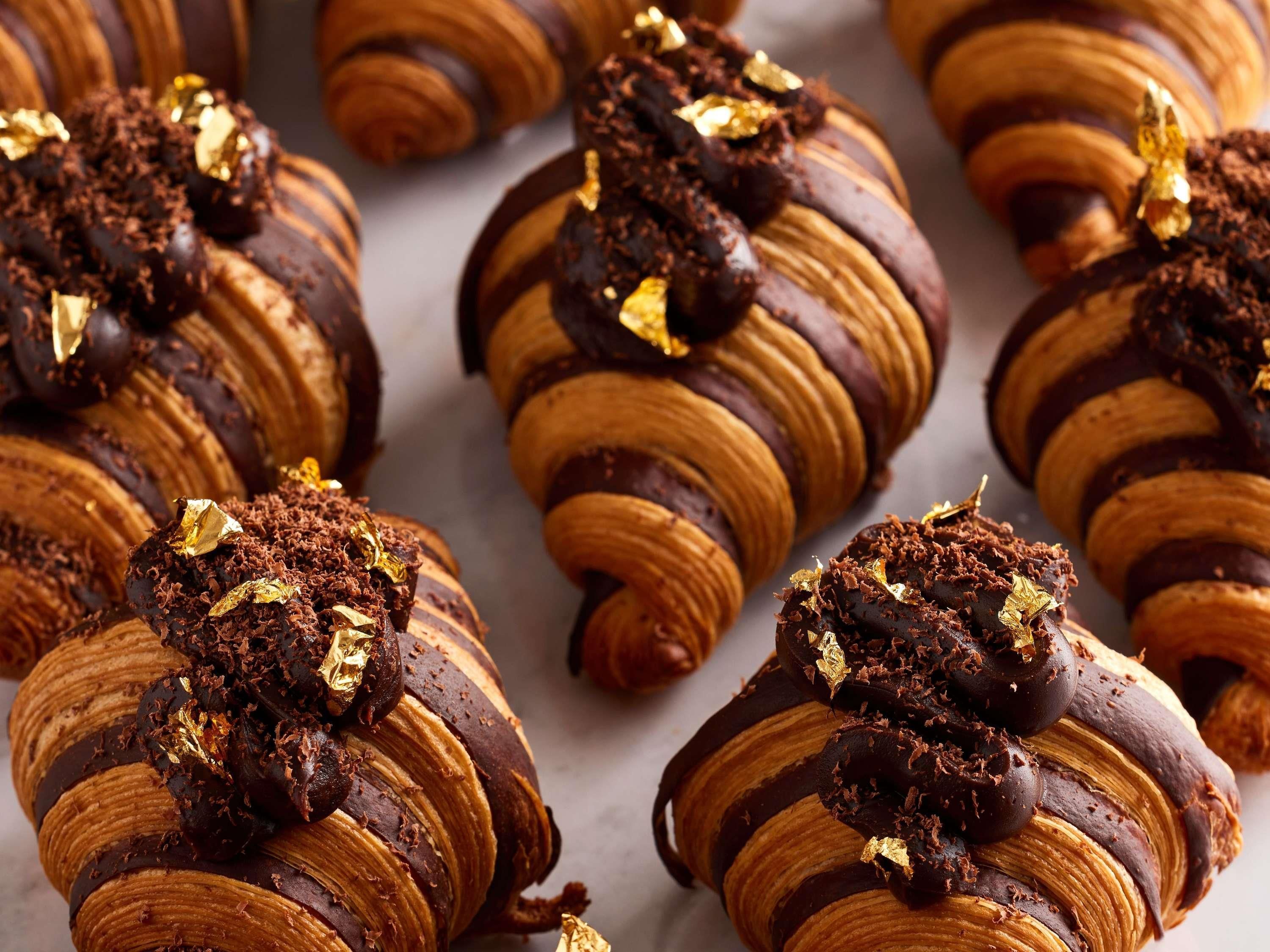 A series of chocolate-covered croissants with gold leaf accents.