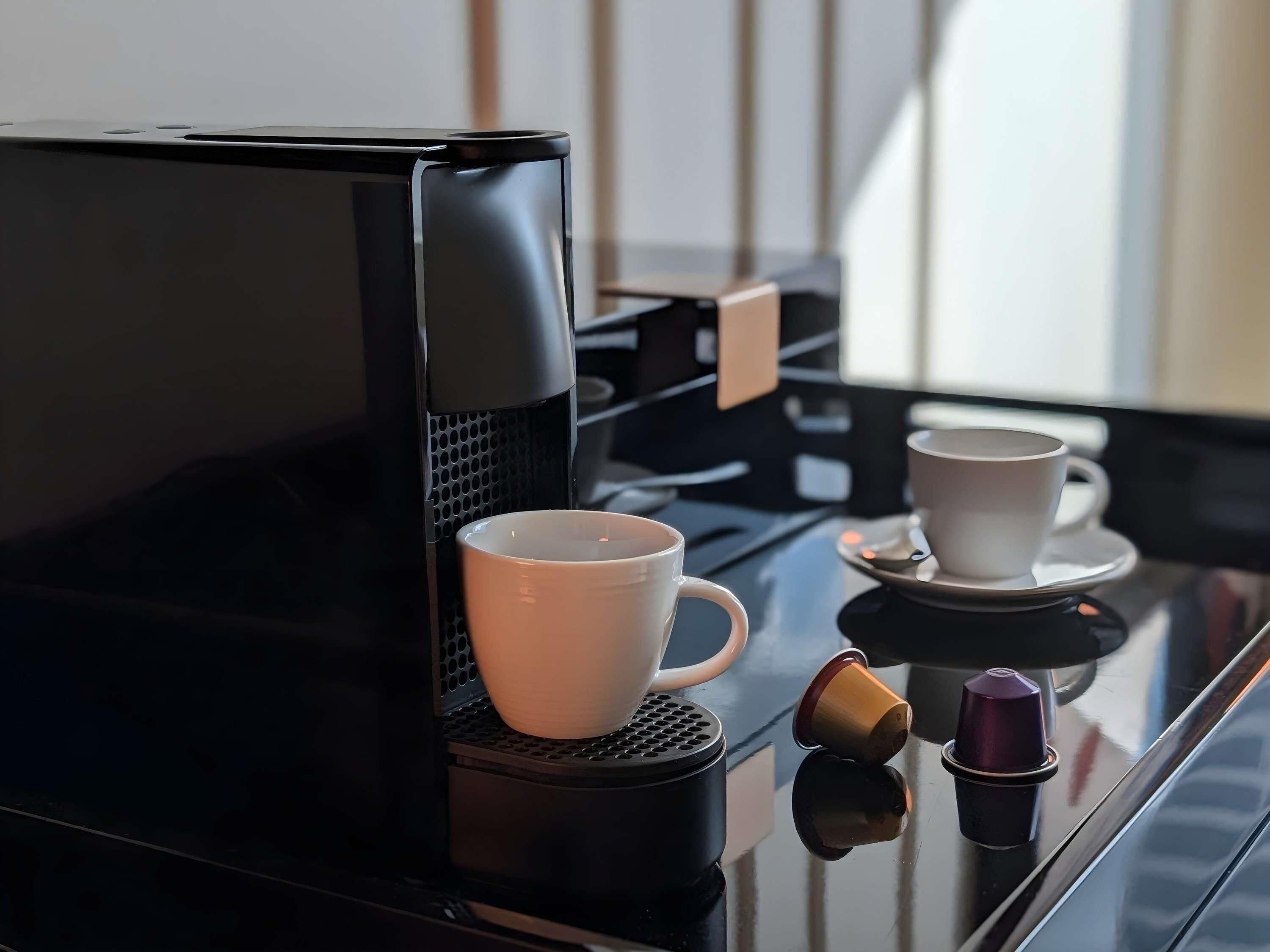 A coffee machine with two cups on a reflective surface.