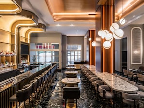A bar area with a long counter, multiple seating options, and a view of the street through large windows.
