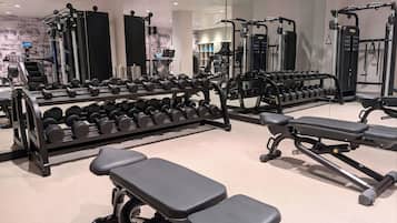 Un gimnasio con diverso equipo de ejercicio, como mancuernas, bancos y máquinas de pesas.