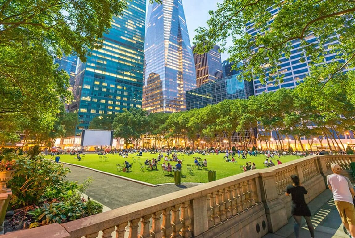 A park with a stone balustrade, surrounded by modern buildings and trees.
