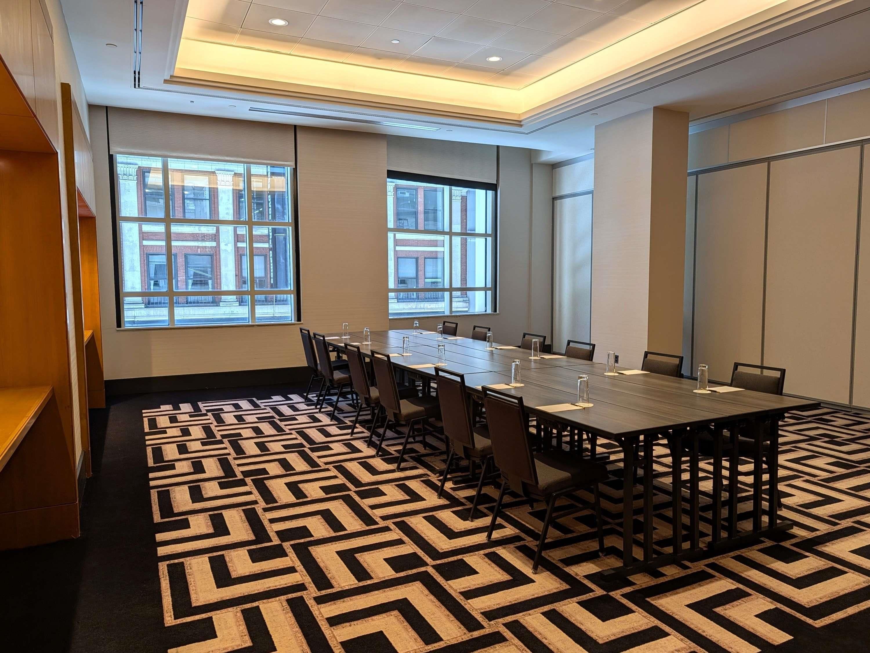 A conference room with a long table, chairs, and large windows.