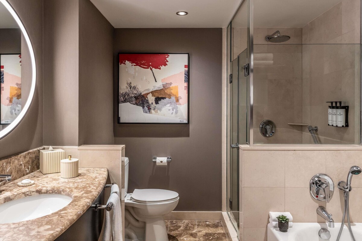 Un baño moderno con lavamanos, inodoro y ducha con mampara de vidrio de mármol.
