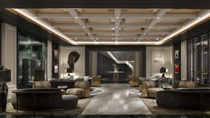 A spacious lobby with a central marble floor, modern furniture, and a staircase leading to upper levels.