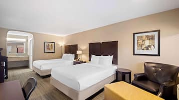 Quarto de hotel com duas camas, uma escrivaninha, uma cadeira, uma mesinha e um quadro na parede.