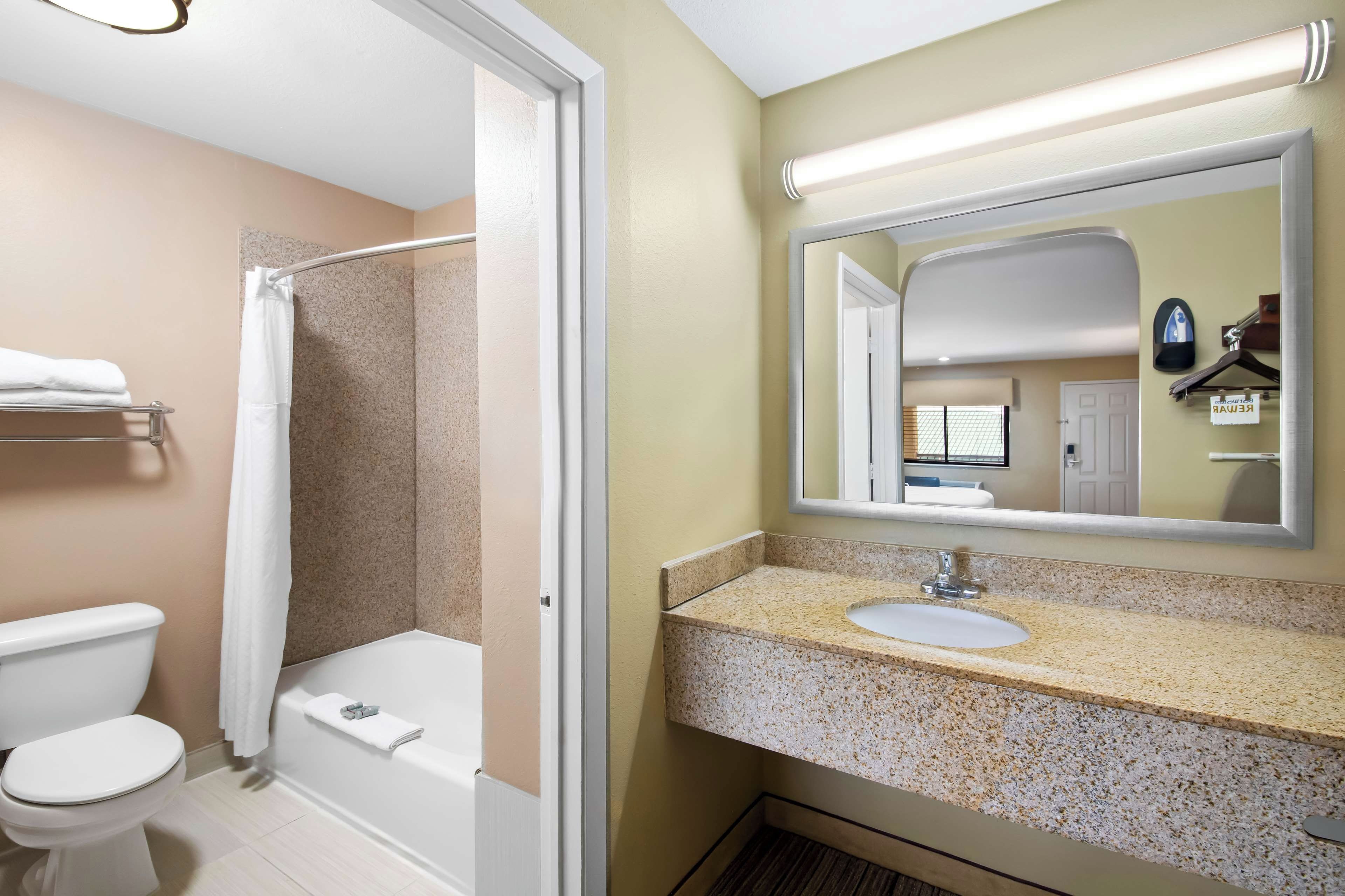 A bathroom with a shower, toilet, sink, and a mirror.