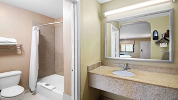 A bathroom with a shower, toilet, sink, and a mirror.