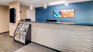 A reception area with a counter, a magazine rack, and a large abstract painting on the wall. - Best Western Cedar Inn (Cedar Park)