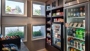 A kitchenette with a refrigerator stocked with beverages, a microwave, and a coffee machine.