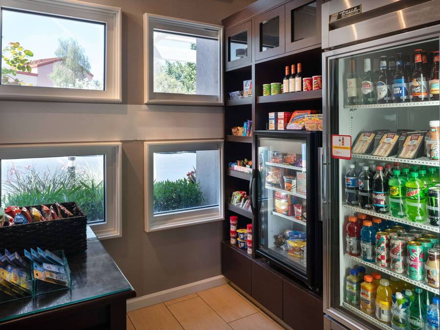Una kitchenette con un refrigerador lleno de bebidas, un microondas y una cafetera.