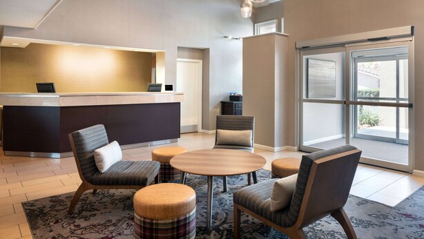 A modern hotel lobby with a reception desk, comfortable seating, and large windows offering a view.