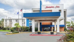 A Hampton Inn hotel with a modern design, featuring a prominent entrance and a parking lot. - Hampton Inn Seattle/Southcenter (Tukwila)