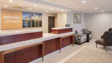 A reception area with a wooden welcome sign, a marble counter, and a seating area with patterned cushions.