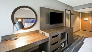 A hotel room with a flat-screen TV mounted on the wall, a desk with a lamp, a microwave, and a small refrigerator. - Hampton Inn Seattle/Southcenter (Tukwila)