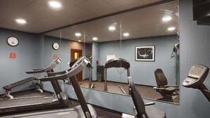 A gym with treadmills, a stationary bike, and a mirror reflecting the room.