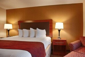 A hotel room with a large bed, two bedside tables, and a red upholstered chair. - Days Inn by Wyndham Indiana PA Near IUP (Indiana)