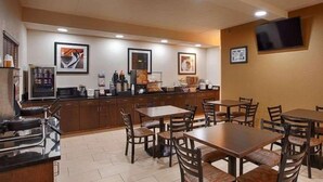 A restaurant with wooden tables and chairs, a counter with food items, and framed pictures on the walls.