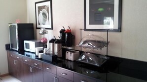 A kitchenette with a microwave, toaster, coffee maker, and a glass display case.