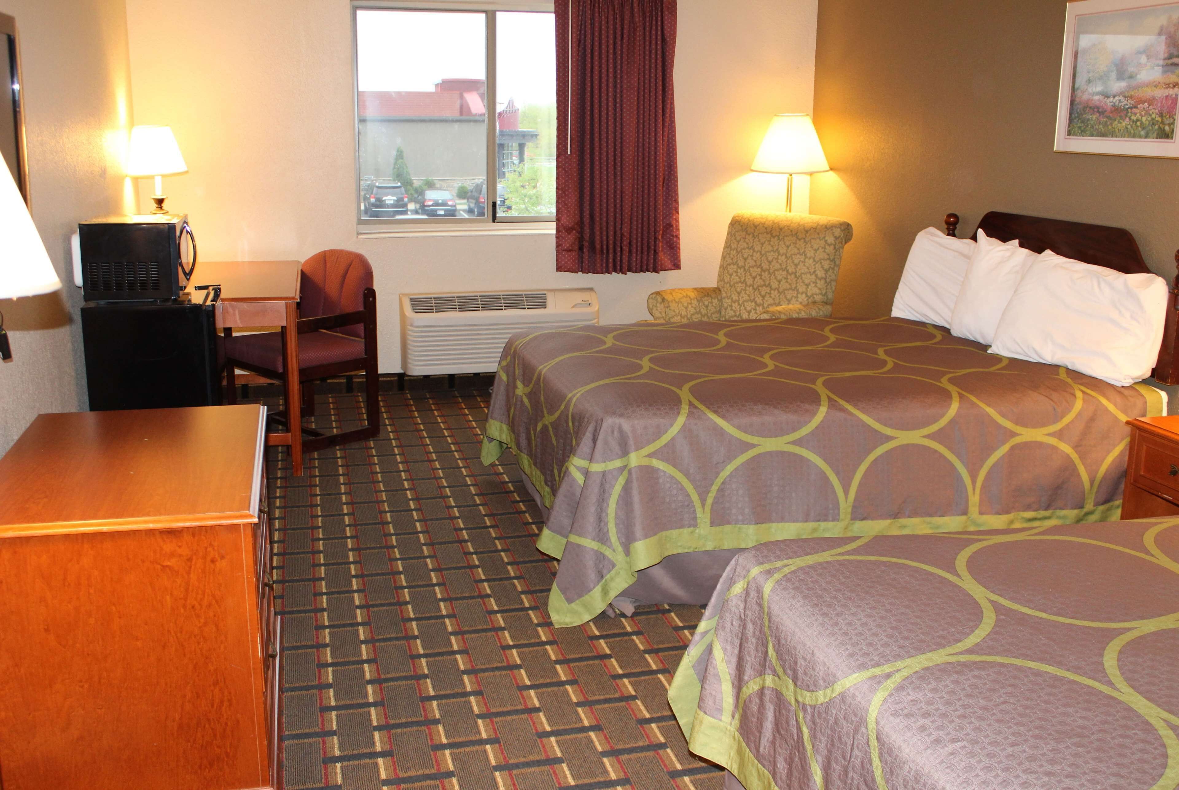 Een hotelkamer met een bed, twee stoelen, een bureau en een televisie.