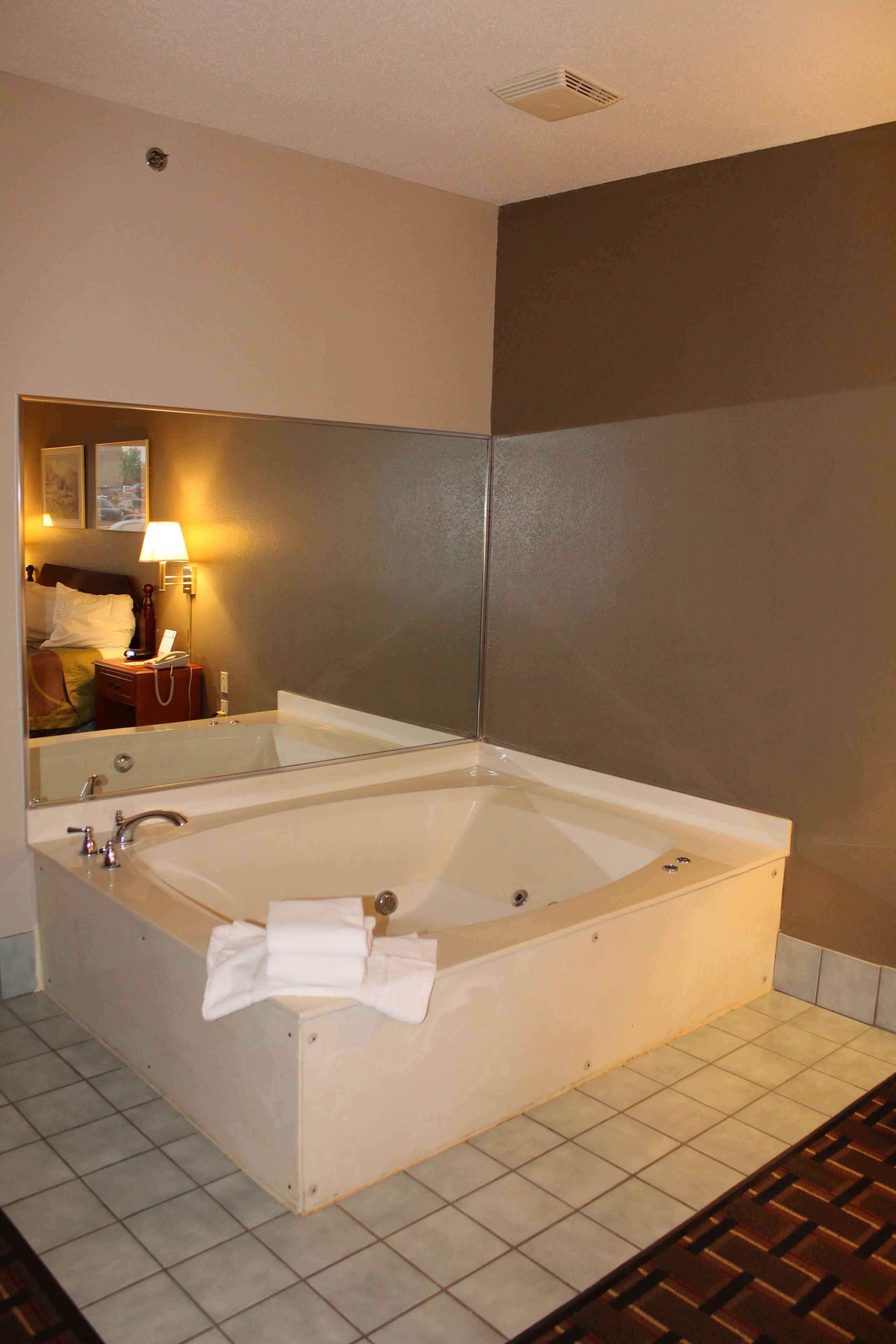 A large, rectangular bathtub in a hotel bathroom with a mirror above it.