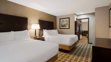 A hotel room with two beds, a nightstand with a lamp, a painting on the wall, and a patterned carpet.